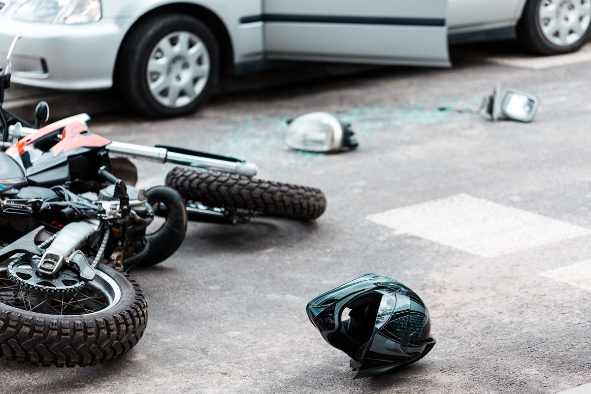 A motorcycle and helmet laying on the ground after a crash