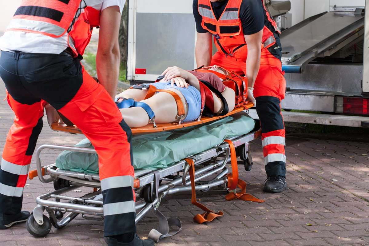 An injured person on a stretcher being lifter by two emergency responders